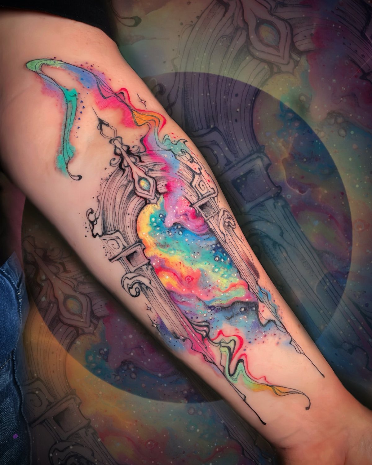A vibrant watercolor tattoo of an ornate cosmic portal on a person's forearm.