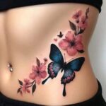 A blue butterfly and pink floral tattoo decorating a woman's stomach and side.