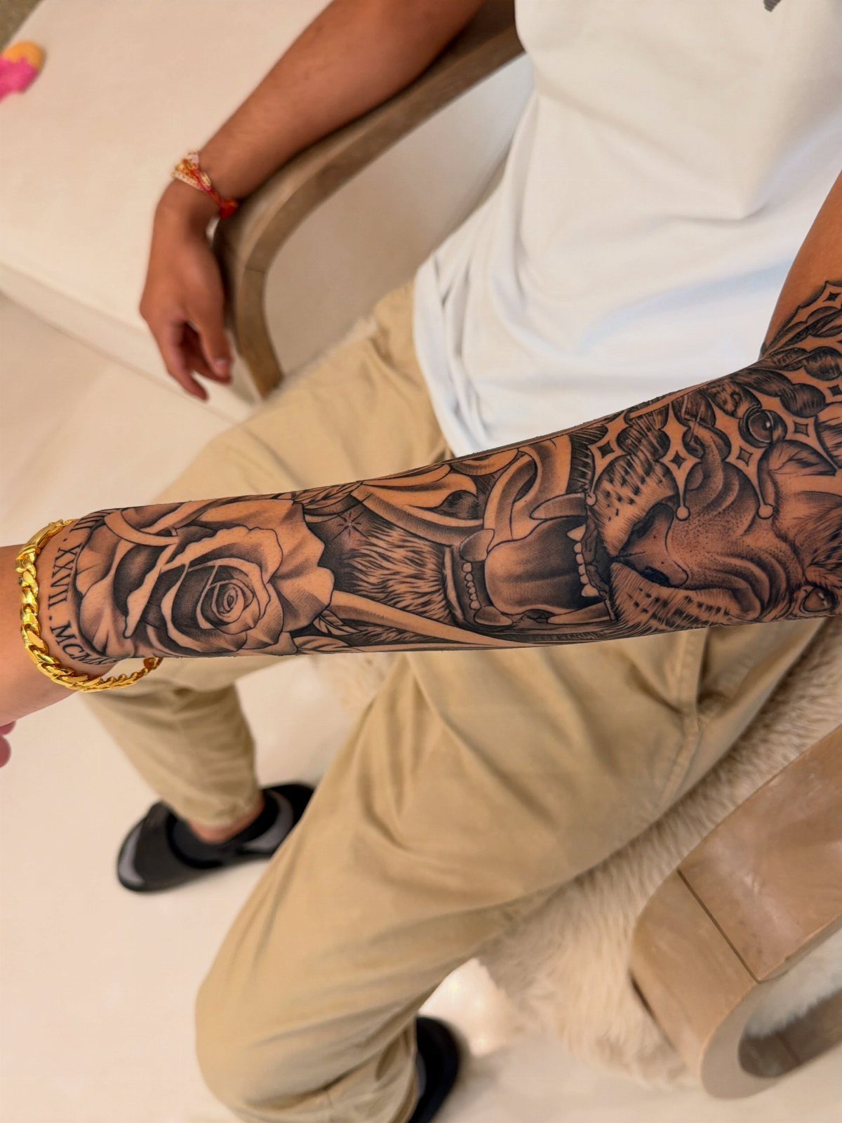 A person's arm displaying a detailed black and grey tattoo sleeve with roses and skulls.