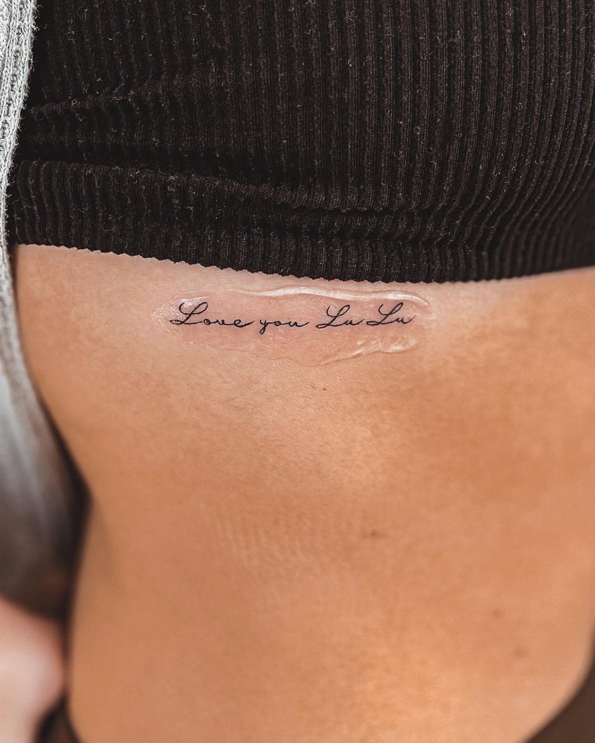 A small cursive text tattoo reading 'Love you Lu Lu' on a person's side ribs.