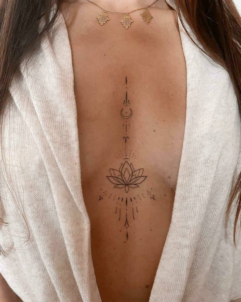 A fine-line lotus and moon tattoo centered on a woman's sternum.